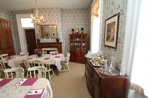 A vintage dining room with floral wallpaper, a chandelier, wooden furniture, and elegantly set tables.
