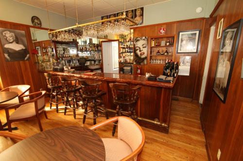 A cozy bar with wooden decor, shelves of liquor, and framed photos, including a portrait of a famous actress.