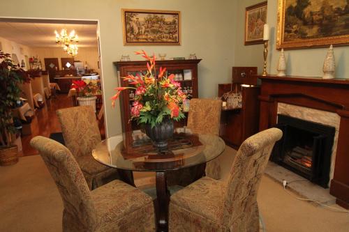 A cozy dining area with a round table, four patterned chairs, and a floral centerpiece near a fireplace.