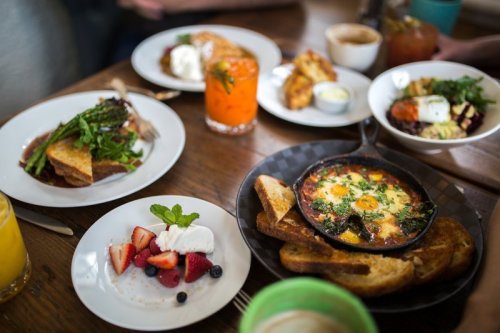A table set with various brunch dishes, including a skillet with eggs, toast, fruit, and drinks.