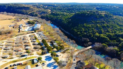 Aerial view of a river winding through green hills, with campsites and trees along the banks.