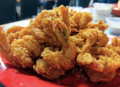 A close-up of a plate piled high with crispy, golden fried shrimp.