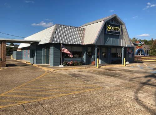 A blue building with a metal roof, featuring a sign that reads "Scott's," and an American flag outside.