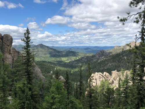 A scenic view of lush green mountains and rocky formations under a partly cloudy sky.