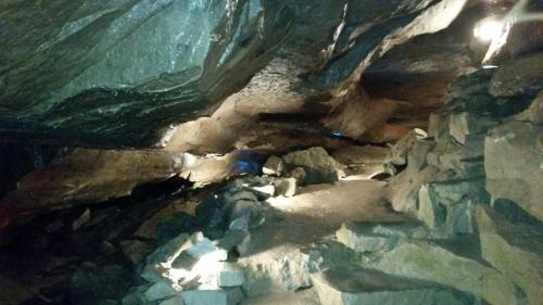 A dimly lit cave interior with rocky formations and scattered stones, illuminated by soft lights.