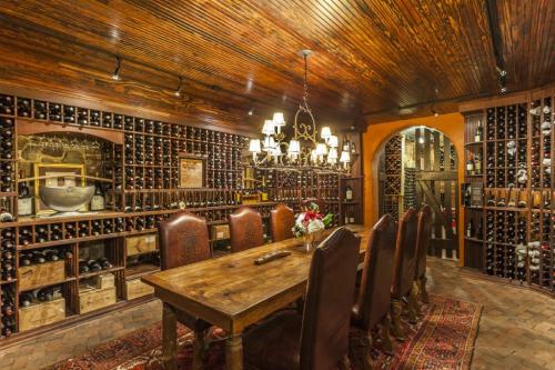 A cozy wine cellar featuring wooden shelves filled with bottles, a rustic dining table, and elegant lighting.