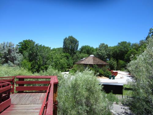 A wooden deck overlooks a lush green area with a round, thatched-roof building in the distance.