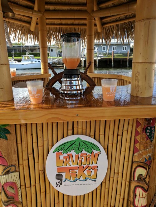A tiki bar with a blender and two cups on a bamboo counter, featuring a logo for "Cruisin' Tiki."