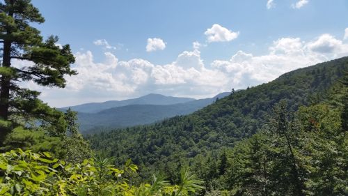 A scenic view of lush green mountains under a blue sky with fluffy clouds.
