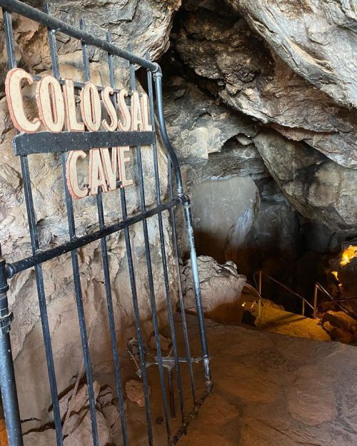 Entrance gate to Colossal Cave, surrounded by rocky walls and a staircase leading into the cave.