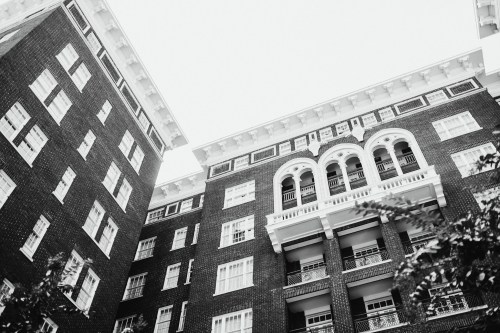 A low-angle view of a historic brick building with ornate balconies and architectural details against a bright sky.