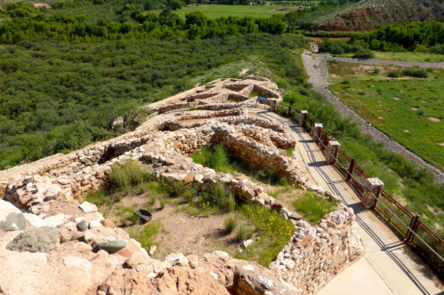 Aerial view of ancient stone ruins surrounded by lush greenery and pathways in a natural landscape.