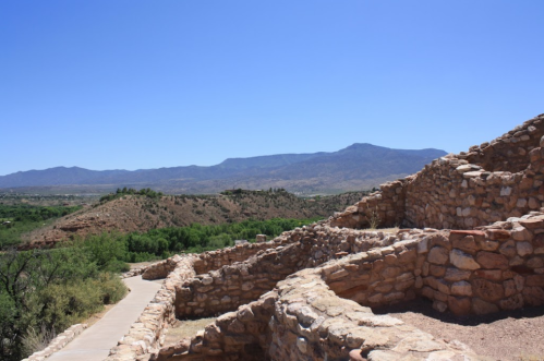 A scenic view of stone ruins with mountains in the background under a clear blue sky.