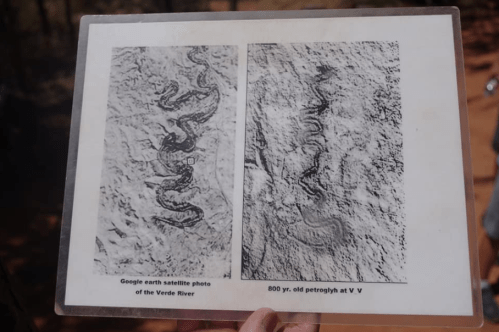 A person holds a sign showing a satellite photo of the Verde River and an 800-year-old petroglyph.