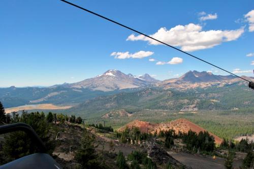 A scenic view of mountains and valleys under a clear blue sky, with a cable line in the foreground.