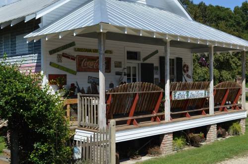 A charming porch with wooden chairs, decorated with vintage signs, on a quaint house surrounded by greenery.