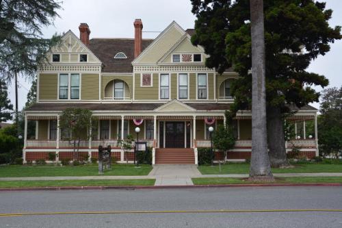 A large, historic Victorian-style house with green siding, decorative trim, and a spacious front porch.