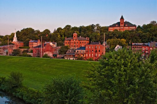 Historic buildings on a hillside, with lush greenery and a clear sky in the background.