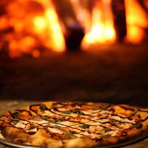 A freshly baked pizza with toppings, set against a warm, glowing fire background.