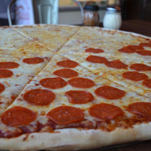A large pizza topped with melted cheese and pepperoni slices, served on a wooden table.