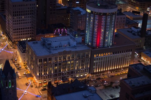 Aerial view of a city at night, showcasing illuminated buildings and streets with colorful lights.