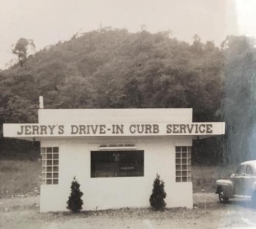 Black and white photo of "Jerry's Drive-In Curb Service" building with a mountainous background.