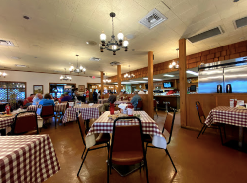A cozy restaurant interior with checkered tablecloths, wooden beams, and patrons enjoying their meals.