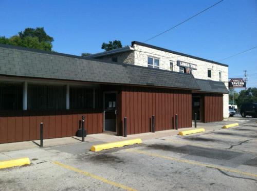 A brown and stone building with a sign for a tavern, featuring a parking lot and clear blue sky.