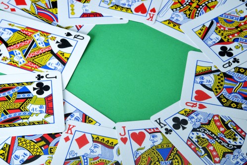 A circle of playing cards featuring kings, queens, and jacks, surrounding a blank green space in the center.