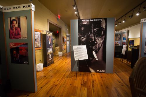 Interior view of an exhibition featuring posters and displays, including "The Last Soul Company" and various artists.