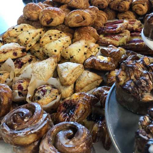 A variety of baked goods including croissants, pastries, scones, and cinnamon rolls arranged on a table.