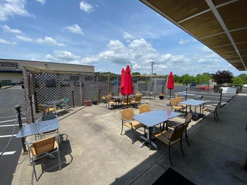 Outdoor dining area with tables and red umbrellas, surrounded by a lattice fence and a clear blue sky.