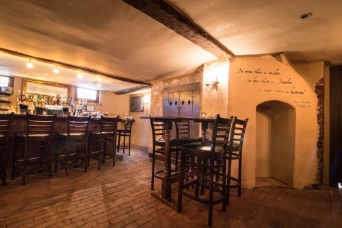 Cozy bar interior with wooden beams, high stools, and a quote on the wall, creating a warm, inviting atmosphere.