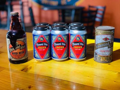 A bottle of Bock beer and four cans of Diamond State Lager on a wooden table.