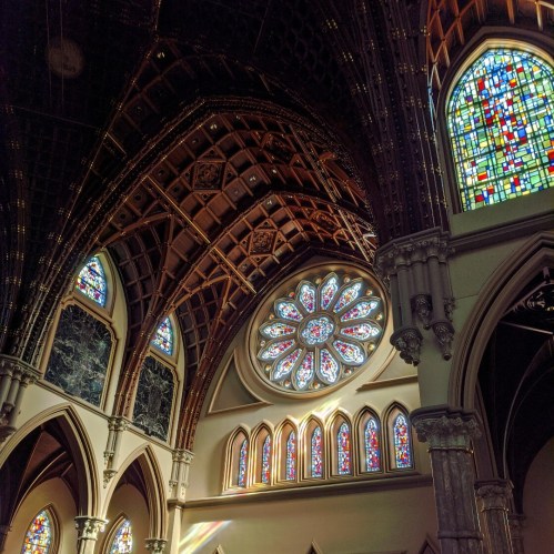 Interior of a church featuring intricate wooden beams and colorful stained glass windows.