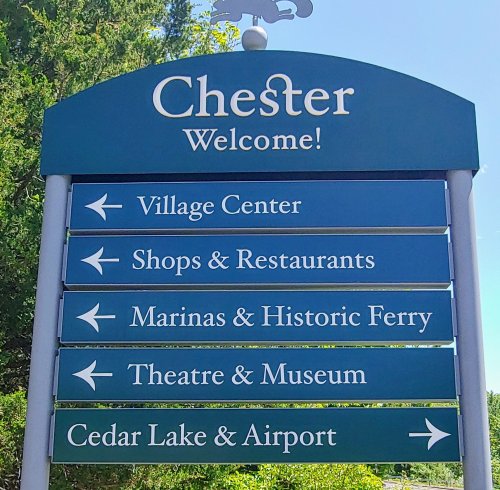 Signpost welcoming visitors to Chester, with directions to Village Center, Shops, Marinas, Theatre, and Cedar Lake.