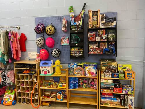 A colorful display of toys, games, and sports equipment in a thrift store, with shelves and bins organized neatly.