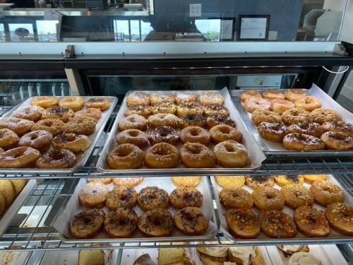 A display case filled with various donuts, including glazed, chocolate, and sprinkled varieties.