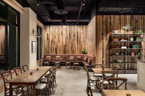 Cozy restaurant interior featuring wooden walls, a plush seating area, and rustic tables and chairs.