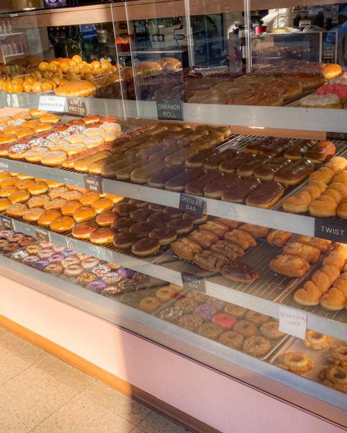 A display case filled with various types of donuts, including glazed, chocolate, and sprinkled varieties.