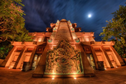 A majestic pyramid structure illuminated at night, with intricate carvings and a bright moon in the sky above.
