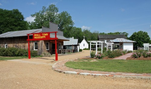 A quaint small town in Mississippi featuring rustic buildings, a church, and landscaped gardens.