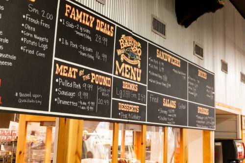 Menu board displaying family deals, meat options, sandwiches, drinks, desserts, and salads at a restaurant.