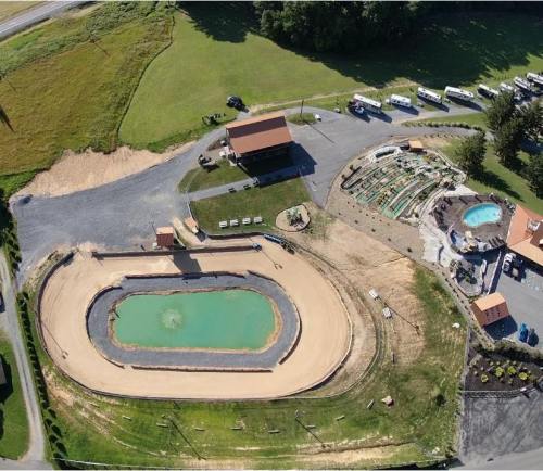 Aerial view of a recreational area featuring a green pond, mini-golf, and parking for trailers.