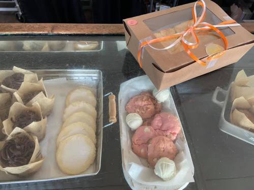 A display of assorted baked goods, including cookies and a boxed treat tied with an orange ribbon.