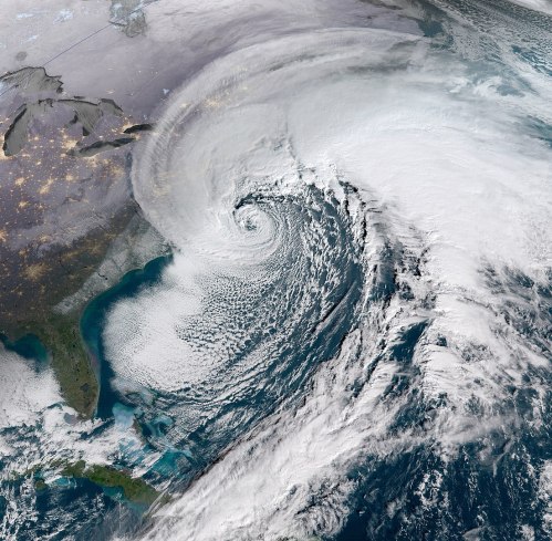 Satellite image of a large storm system over the Atlantic Ocean, with swirling clouds and coastal regions visible.
