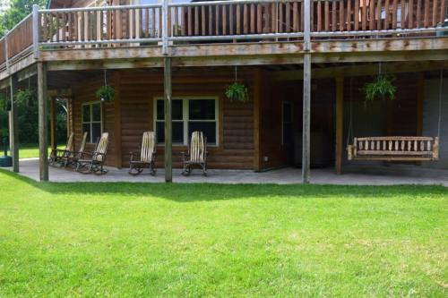 A wooden porch with rocking chairs and a swing, overlooking a green lawn.