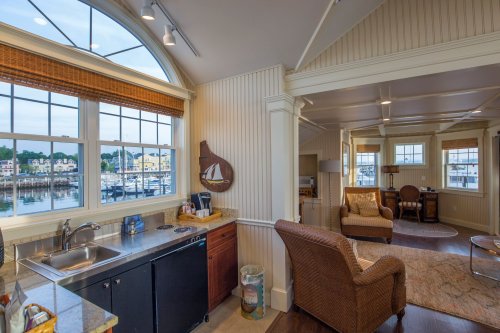Cozy interior of a waterfront home with a kitchen, seating area, and large windows overlooking the marina.