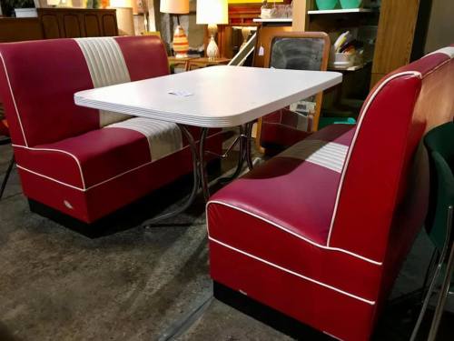A retro diner-style booth with red vinyl seats and a white table in a vintage shop setting.