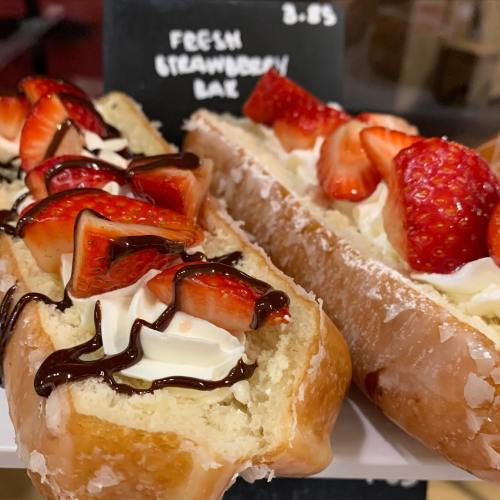 Two fresh strawberry desserts on a plate, topped with whipped cream and chocolate drizzle. Price tag visible.